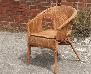 hazel brown rattan and wooden chair at the edge of a road with coffee cup under delicate sunlight