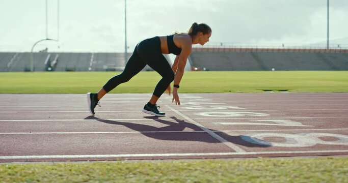 Attractive young woman sprinting down the track at the stadium, epic running workout, fitness lifestyle