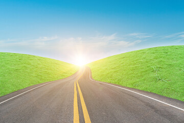 Fototapeta premium Asphalt road and green grass field in countryside on sunny day.