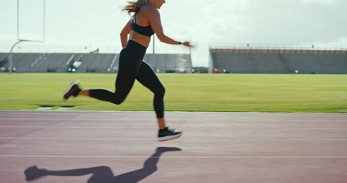 Attractive strong young woman sprinting at the track, epic running workout, fitness lifestyle