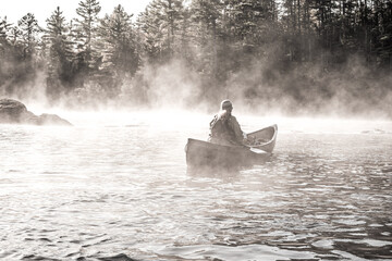 A solo paddler comtempates the morning mist on the Lower Madawaska River on a  fall day in Eastern...