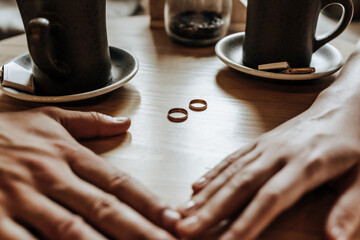 Man and woman couple of newlyweds hold hands with rings in a cafe with a cup of coffee. The bride and groom are in love