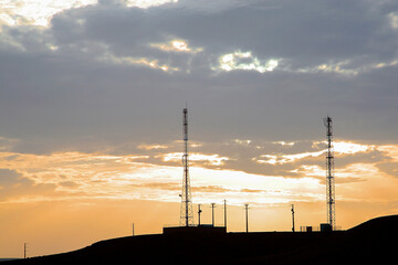 Orange sunset with silhouette of telecommunication towers and phone cables in Essaouira. Morocco