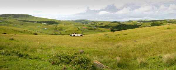 Obraz premium Panoramic view of a wreck car in the middle of a field on the way to Durban. Wild coast - South Africa