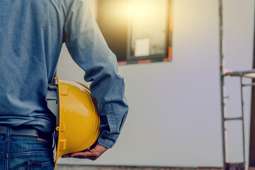 Contractor holding yellow helmet on site building construction , Engineer hold hard hat