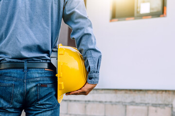 Contractor holding yellow helmet on site building construction , Engineer hold hard hat