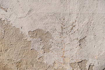 Weathered wall plaster with cracks and imperfections background. Full frame texture of white render. Material surface pattern with dirty and damage on a house.