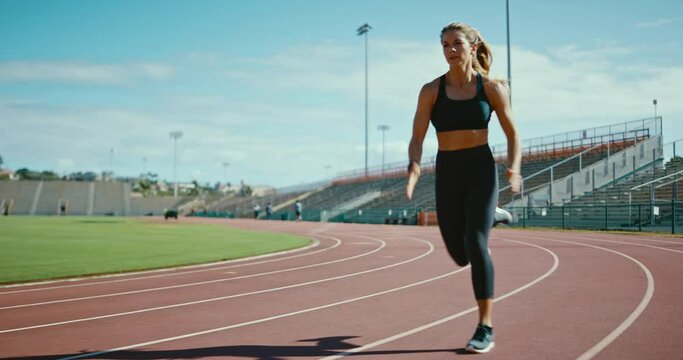 Young athletic woman running at stadium track, working hard and pushing the limits of her body, sprinting to the finish line, active lifestyle