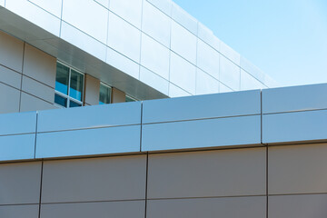 Obraz premium The exterior wall of a contemporary commercial style building with aluminum metal composite panels and glass windows. The futuristic building has engineered diagonal cladding steel frame panels.