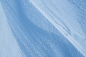 Snow texture. Wind sculpted patterns on snow surface. Wind in the tundra and in the mountains on the surface of the snow sculpts patterns and ridges (sastrugi). Arctic, Polar region. Winter background