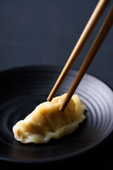 Steamed wonton dumpling on black dish eating by using chopsticks, Asian food