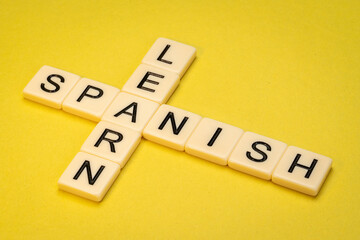 learn Spanish  crossword in ivory letter tiles against yellow textured  paper