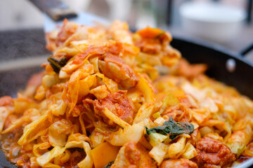 Close up fried Korean food called “Dakgalbi”with spade of frying pan,it's Korean style Chicken with spicy plate.The Korean favorite food from chicken stir with spicy sauce,vegetable in big hot pan.