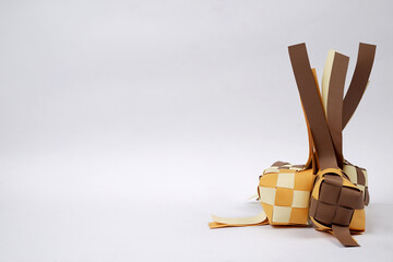 Replica of steamed diamond shaped rice made of colored cardboard isolated on brown background. Steamed ketupat-shaped rice is synonymous with the month of Ramadan.