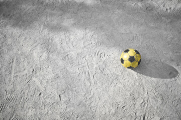 公園の砂場に忘れられた黄色いサッカーボール