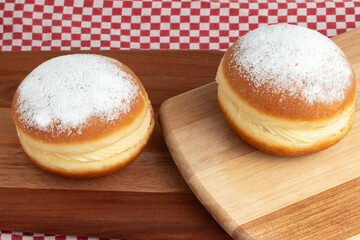 Berlin Balls or Brazilian sonho on cutting board.  Portuguese pastry, a  fried doughnut stuffed with sweet eggy cream and sprinkled sugar