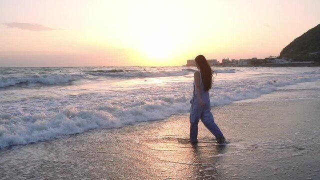 夕日が綺麗な海辺で遊ぶ若い女性