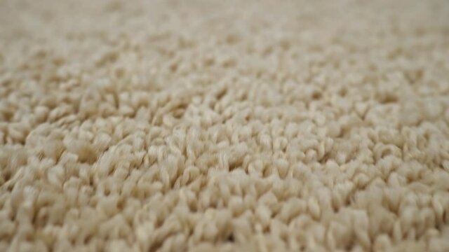 Close-up of light beige carpet camera movement.
