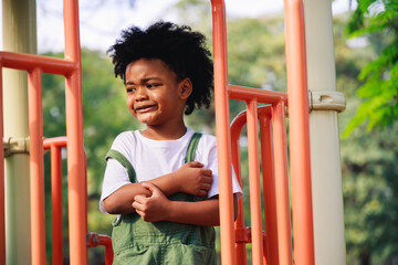 Cute African American little kid boy funny while playing on the playground in the daytime in the spring season. Outdoor activity. Playing make-believe the concept. Outside education