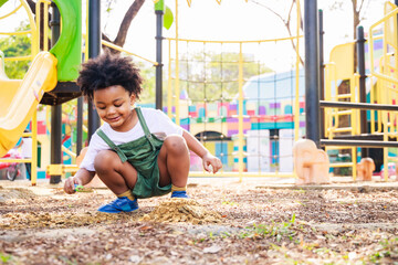 Cute African American little kid boy having fun while playing on the playground in the daytime in summer. Outdoor activity. Playing make believe concept. Outside education - Powered by Adobe