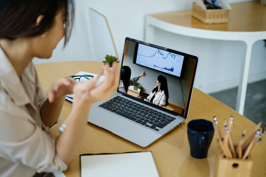 Rear view of female employee meeting via video call with employee brief the stock market chart.
