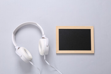 Stereo headphones and blank mini chalk board for copy space on gray background