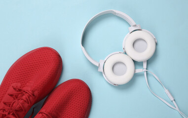 Headphones and red sports shoes on a blue background. Sport concept. Running & active lifestyle accessories. Top view