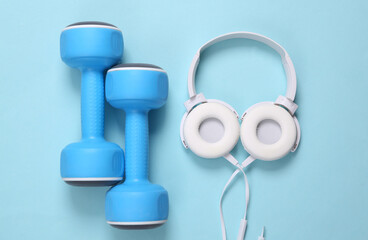 Dumbbells and headphones on a blue background. Fitness accessories. Top view