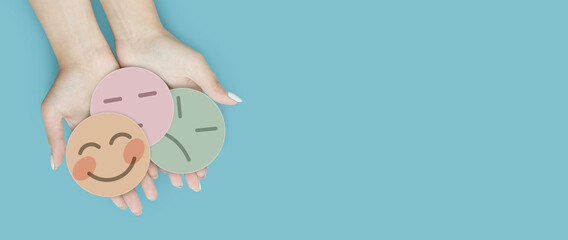 Hand holding paper cut happy smile face on blue background, positive thinking, mental health assessment , world mental health day concept	