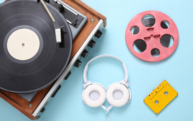 Flat lay musical composition. Vinyl record player, stereo headphones, audio cassette and reel on...