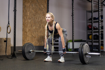 Fototapeta na wymiar Muscular Woman performs deadlift with weight in modern functional gym