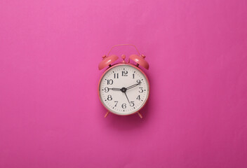 Pink alarm clock on pink background. Minimalism. Top view. Flat lay