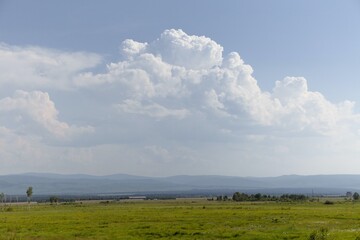 plain landscape with cloudy sky, blue mountains in the background