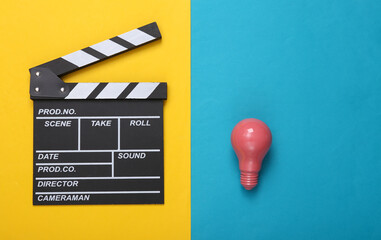Movie clapperboard and Pink light bulb on blue yellow background. Creative cinema layout. Fresh...