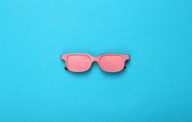 Pink sunglasses on blue background. Top view. Flat lay. Concept art. Minimalism