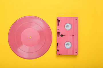 Creative retro 80s layout. Pink vinyl record and vhs on yellow background. Minimalism. Flat lay....