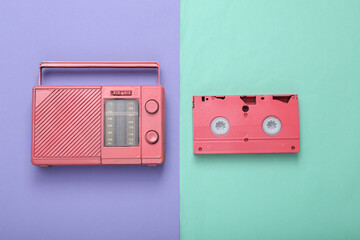 Pink radio receiver and video cassette on purle blue background. Minimal retro concept. Top view. Flat lay