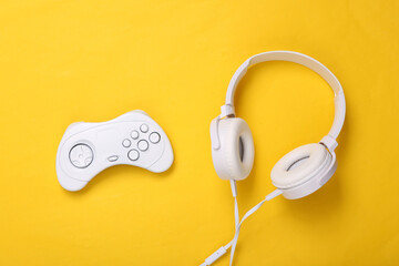 White headphones with gamepad on yellow background. Creative gaming layout. Top view. Flat lay