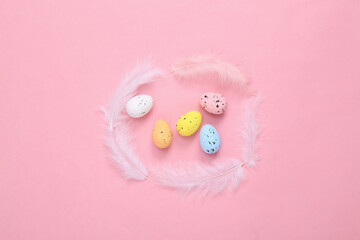 Easter composition of colored eggs and feathers on a pink background. Top view. Flat lay