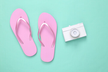 Minimalism travel layout. Flip-flops and white camera on mint blue background. Top view. Flat lay