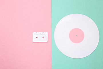 Music creative layout. White vinyl record and audio ccassette on pink blue background. Minimalism. Top view. Flat lay