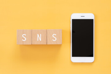 SNS｜「SNS」と書かれた積み木とスマートフォン