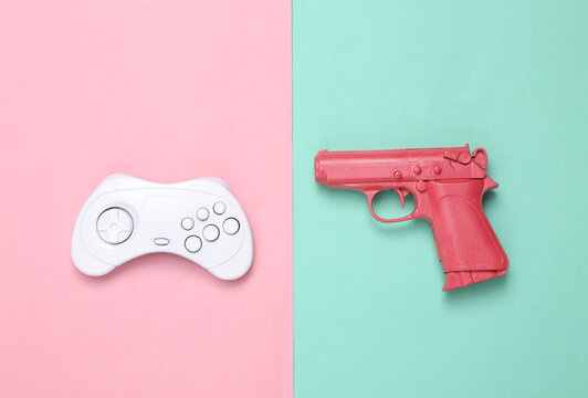 Minimalism creative layout. Pink gun and gamepad on pink blue background. Minimalism. Top view. Flat lay