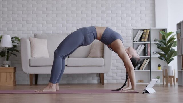 Asian woman look laptop practice yoga bridge online course at home