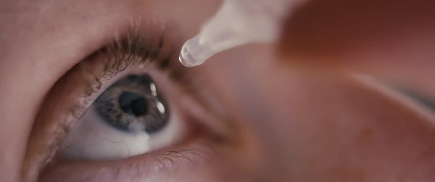 Medical eye drops care in woman's hand blue macro medicine close up