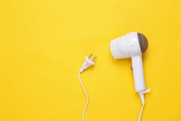 White hair dryer on a yellow background. Hair care, hair style. Top view. Flat lay