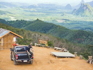 car trip concept from Solo traveler sitting alone on pickup truck and enjoying view of nature...