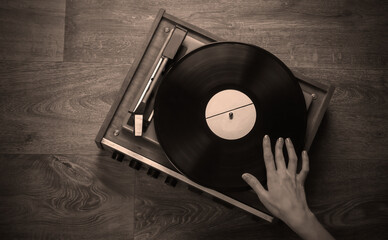Female hands set up a retro vinyl record player on a wooden floor. Music lover, 70s, nostalgia, top...