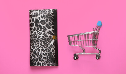 Shopping trolley with wallet on pink background. Top view. Minimalism shopping concept. Flat lay