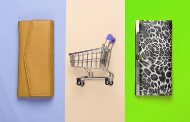 Shopping trolley with wallets on colored background. Top view. Minimalism shopping concept. Flat lay